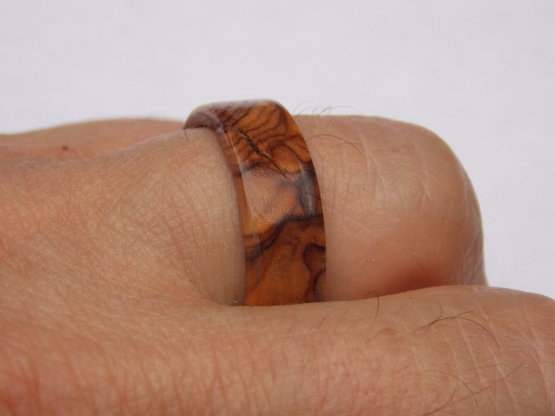 Puede incluir: Un anillo de madera con un patr&oacute;n de veta de madera marr&oacute;n y marr&oacute;n oscuro.