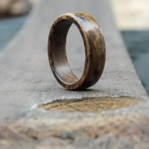 K&ouml;nnte beinhalten: Ein Holzring mit dunkelbrauner Oberfl&auml;che. Der Ring hat eine glatte, polierte Oberfl&auml;che und ein schlichtes Design.