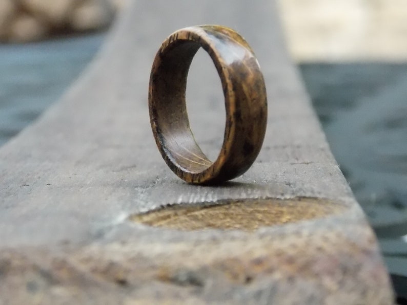 K&ouml;nnte beinhalten: Ein Holzring mit dunkelbrauner Oberfl&auml;che. Der Ring hat eine glatte, polierte Oberfl&auml;che und ein schlichtes Design.