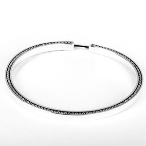 May include: A silver bangle bracelet with a beaded edge.