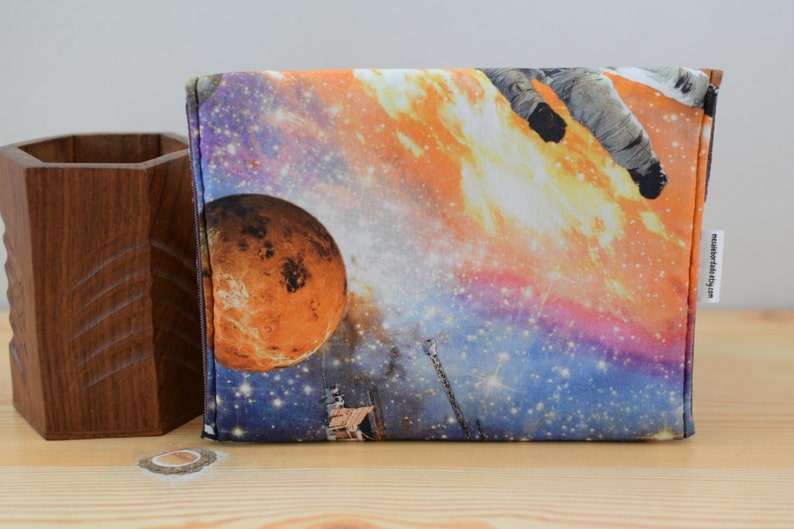 May include: A colorful zippered pouch with a space-themed design featuring an astronaut, a planet, and stars. The pouch has a black zipper and a white label with the text "www.etsy.com/shop/misterwobbly".