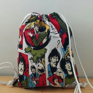 Puede incluir: Una bolsa de cordón blanco con un estampado de cómic colorido con personajes y bocadillos de diálogo. La bolsa tiene cordones de cordón blanco.