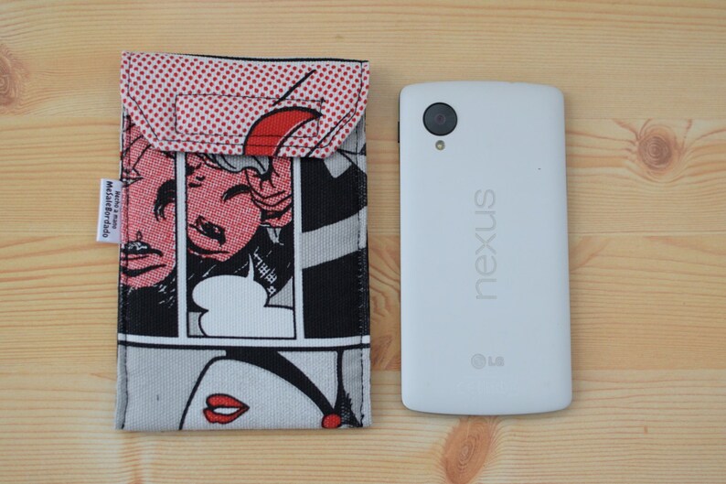 Pu&ograve; includere: Una custodia per telefono bianca con un design a fumetti in rosso, nero e bianco. La custodia ha una patta che si chiude con un bottone a pressione. La custodia per telefono &egrave; accanto a uno smartphone bianco con la parola "nexus" stampata sul retro.