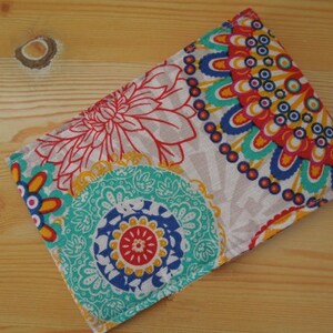 May include: A colorful fabric pouch with a white background and a pattern of blue, red, yellow, and green flowers and circles.