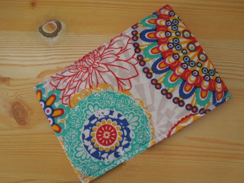 May include: A colorful fabric pouch with a white background and a pattern of blue, red, yellow, and green flowers and circles.