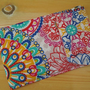 May include: A colorful fabric pouch with a paisley pattern in shades of red, blue, yellow, and green. The pouch has a flap closure and is made of a soft, textured fabric.