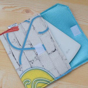 K&ouml;nnte beinhalten: Ein wei&szlig;es Tablet-Computer mit einer blauen und wei&szlig;en Ziegelmusterh&uuml;lle. Die H&uuml;lle hat ein blaues Neon-Design und ein rotes und wei&szlig;es Etikett mit der Aufschrift "Recycled with love".