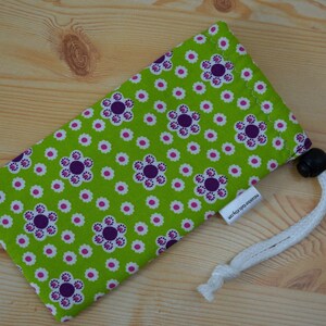 May include: A green and purple floral print drawstring pouch with a white cord and a black toggle. The pouch has a white label with the text "www.hega-design.com".