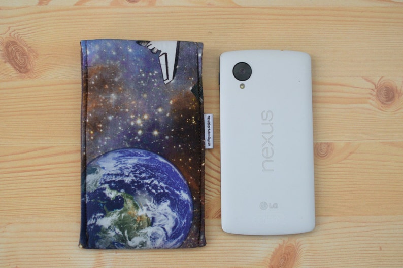 May include: A white Nexus phone case with a galaxy and earth design. The case is made of fabric and has a zipper closure.