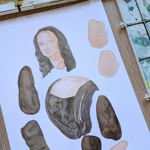 May include: Watercolor painting of the Mona Lisa in pieces on white paper. The painting is in the process of being created, with the face, torso, arms, and legs separated. Watercolor paint trays are in the background.
