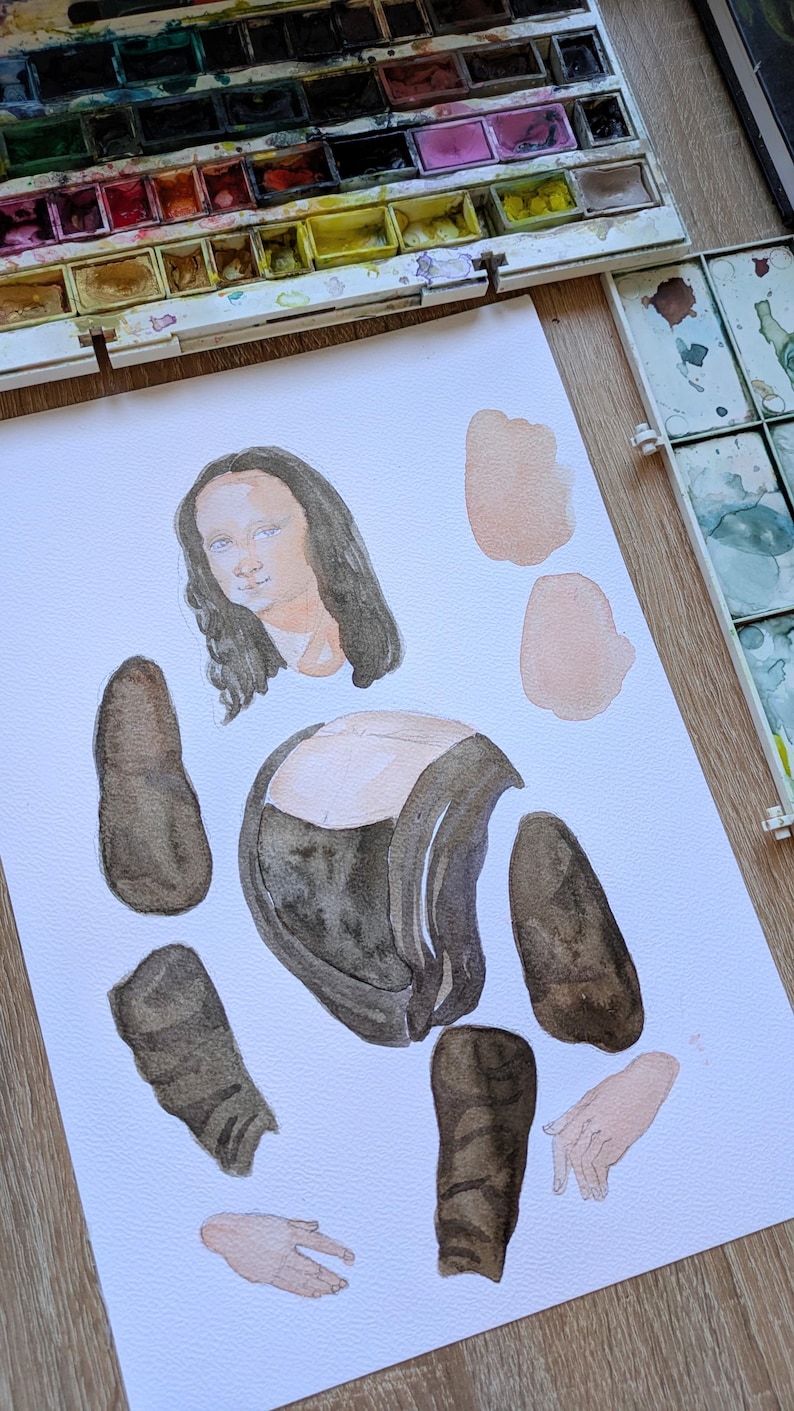 May include: Watercolor painting of the Mona Lisa in pieces on white paper. The painting is in the process of being created, with the face, torso, arms, and legs separated. Watercolor paint trays are in the background.
