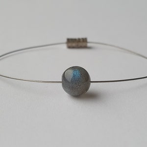 May include: A silver wire bracelet with a single round, iridescent labradorite gemstone bead.