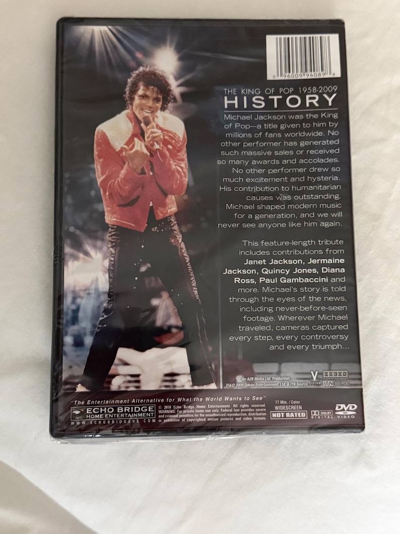 May include: A DVD case for the documentary Michael Jackson: The King of Pop 1958-2009 History. The back cover features a photograph of Michael Jackson in a red jacket and black pants, along with biographical text, a barcode, and technical specifications.