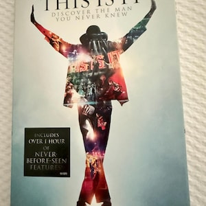 May include: A DVD case for Michael Jackson's This Is It, featuring a silhouette of the performer with arms raised. The cover includes the text "Michael Jackson's This Is It, Discover the Man You Never Knew" and a black box stating "Includes over 1 hour of never-before-seen features!"