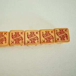 May include: Five vintage playing card dice, each displaying a red King of Hearts design and the letter "K" on a cream-colored background. These dice are likely used for games or collecting.