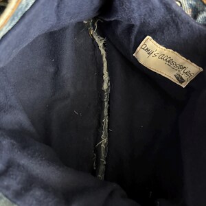 May include: Inside view of a denim bag with a dark blue interior. The bag's interior features a tag that reads "amy's accessories". The bag is made from recycled denim material.