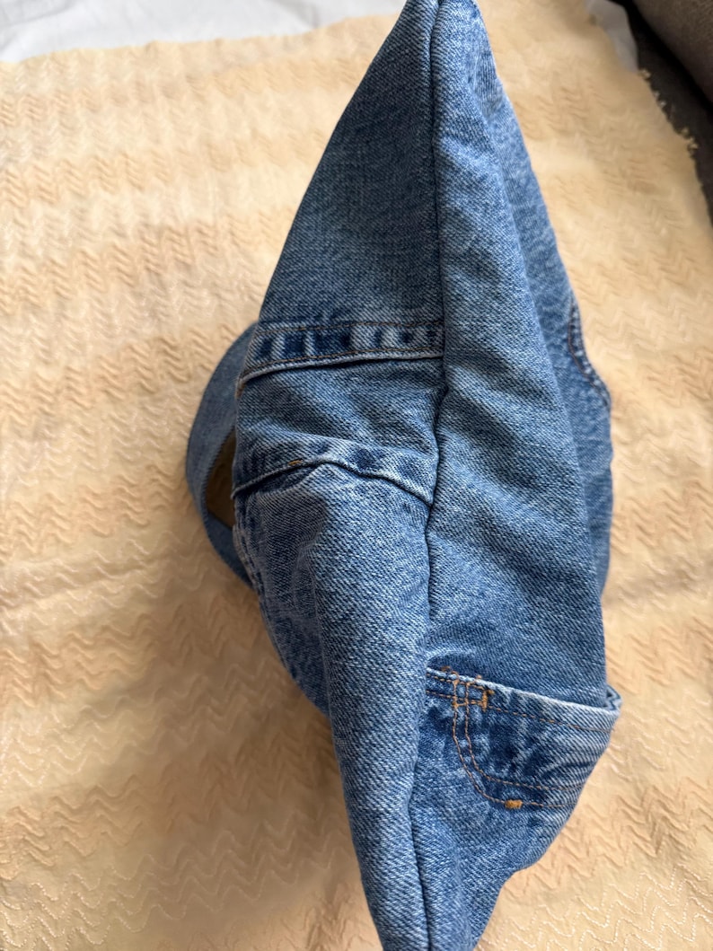 May include: A blue denim hat with a curved brim and a small pocket detail. The hat is made of a classic blue denim material and features visible stitching.