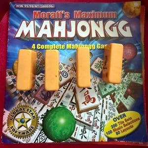 May include: A Mahjongg game set with orange tiles and a green sphere. The game box features the text "Moraff's Maximum Mahjongg" and "4 Complete Mahjongg Games". The box also has the Global Star Software logo and details about tile sets and music selections.