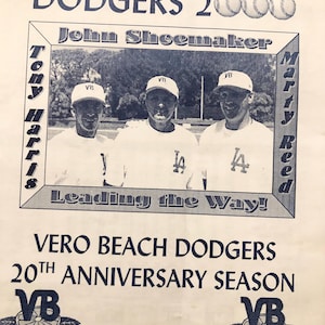 May include: A white paper flyer featuring a blue-ink print of the Vero Beach Dodgers 20th Anniversary Season. It includes a photograph of three individuals in baseball caps, the text Dodgers 2000, and the signature of Tom Lasorda at the top.