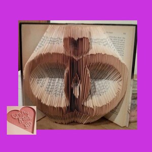 Puede incluir: Una escultura de arte de libro de una mariposa hecha doblando las páginas de un libro. La escultura está hecha de papel marrón y se exhibe en un estante. La escultura se titula "Crafty Home".