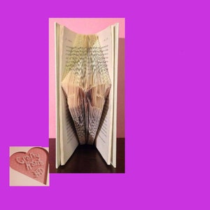 May include: A book with pages folded to create the word "Home". The book is open, revealing the folded design. A small, pink heart-shaped card with the words "Crafty Home" is in the lower left corner.