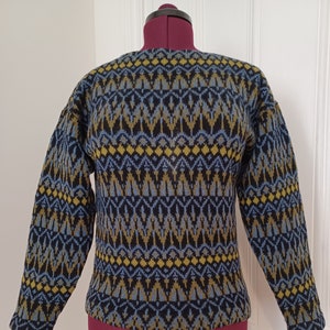 May include: A blue, yellow and black patterned sweater with a crew neck.