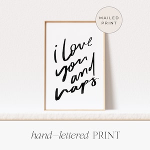 May include: A framed print with the words "i love you and naps" in black script on a white background. The print is in a light brown frame and has the words "hand-lettered PRINT" at the bottom.