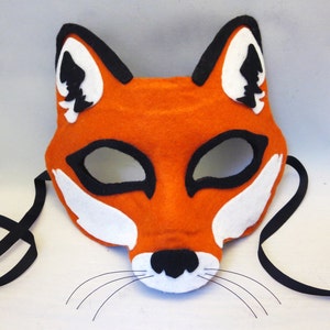 May include: Orange felt fox mask with black felt eyes and white felt accents. The mask has black felt ears and a black felt nose. The mask has a black felt tie.