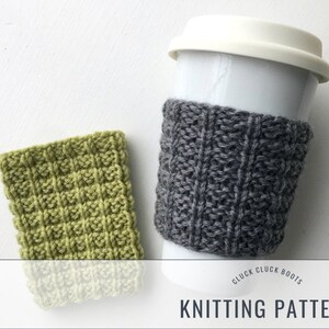 Pode incluir: Um padrão de tricô para um aquecedor de xícara de café cinza e verde. O padrão é chamado de "Cluck Cluck Boots" e é mostrado em um fundo branco.