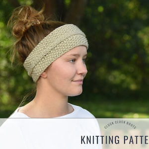 May include: A beige knitted headband with a simple stitch pattern. The headband is worn by a person with brown hair pulled back in a bun. The background is a blurred image of green foliage.