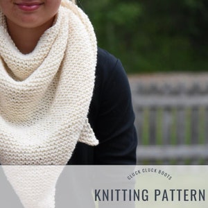May include: A white knitted scarf with a triangular shape. The scarf is worn by a person with a black shirt. The text "Cluck Cluck Boots Knitting Pattern" is visible at the bottom of the image.