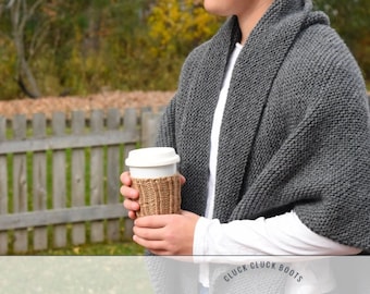 May include: A person wearing a gray knitted shawl and a white shirt, holding a coffee cup with a brown sleeve. The background is a wooden fence and green trees. The text "CLUCK CLUCK BOOTS KNITTING PATTERN" is at the bottom of the image.