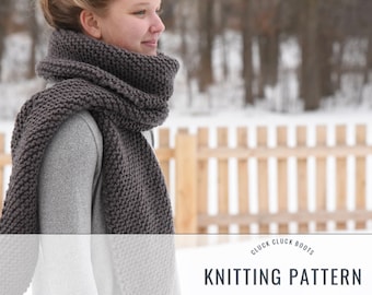 May include: A gray knitted scarf worn by a person in a snowy outdoor setting. The scarf is thick and textured, and the person is wearing a gray sweater. The background includes a wooden fence and snow-covered ground. The text "CLUCK CLUCK BOOTS KNITTING PATTERN" is visible at the bottom of the image.