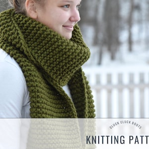 May include: A green knitted scarf with a textured stitch pattern. The scarf is worn by a person in a white shirt, standing in front of a snowy background. The text "Cluck Cluck Boots Knitting Pattern" is visible at the bottom of the image.