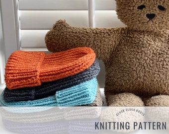 May include: A stack of four knitted hats in orange, gray, blue, and white. The hats are stacked on a white surface with a brown teddy bear in the background. The text "Cluck Cluck Boots Knitting Pattern" is visible at the bottom of the image.