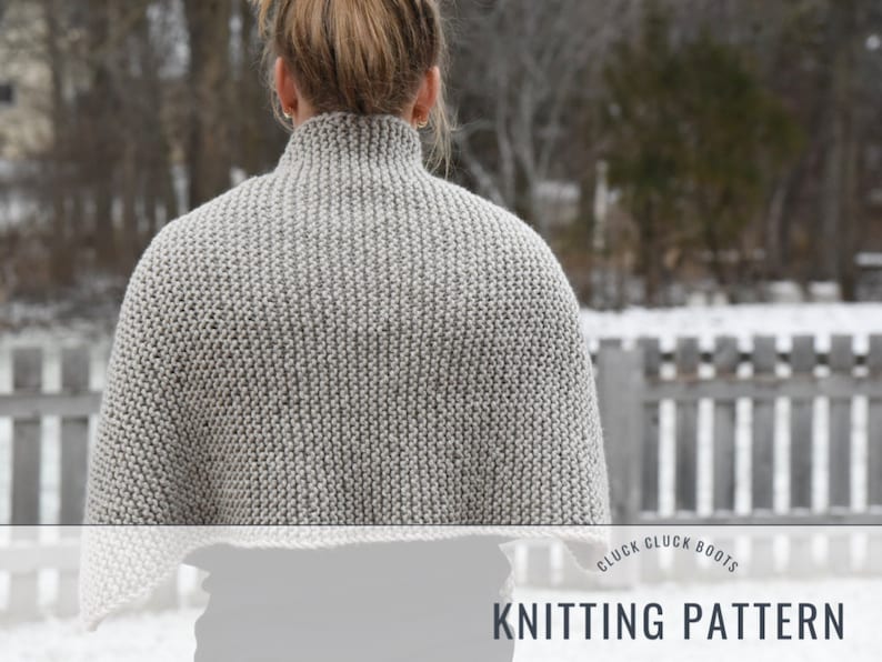 May include: A gray knitted cowl neck sweater with a ribbed texture. The sweater is being worn by a person in a snowy outdoor setting. The text "CLUCK CLUCK BOOTS KNITTING PATTERN" is visible at the bottom of the image.