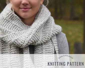 May include: A gray and white knitted scarf with a textured pattern. The scarf is folded and draped around a person's neck. The text "Cluck Cluck Boots Knitting Pattern" is at the bottom of the image.