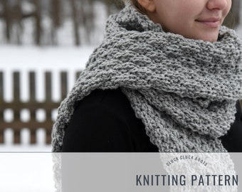 May include: A chunky, gray knitted scarf is draped around the neck. The scarf is made of thick yarn and has a textured appearance. The words "Knitting Pattern" are displayed below the scarf.