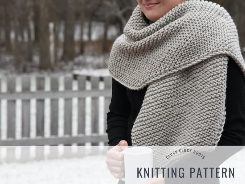 May include: A gray knitted scarf with a simple stitch pattern. The scarf is draped around the neck of a person wearing a black shirt. The text "Cluck Cluck Boots Knitting Pattern" is at the bottom of the image.