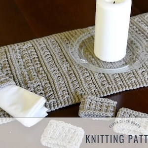 May include: Knitting pattern for a table runner and napkin rings. The pattern is called "Cluck Cluck Boots". The runner and rings are a light brown color.