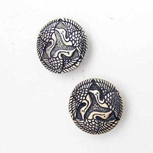 May include: Two silver-toned metal buttons with a circular design featuring three stylized birds in a circular pattern.