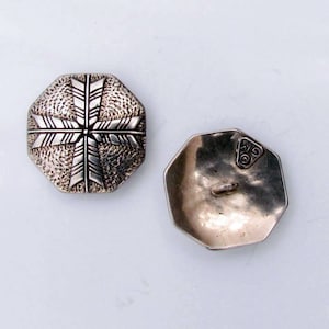 May include: Two silver octagonal buttons with a snowflake design on one side and the letters "W.G." on the other side.