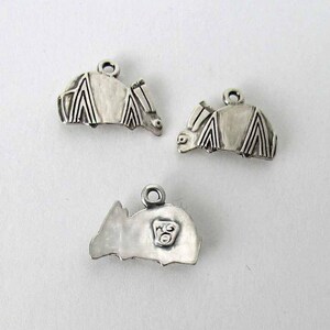 May include: Three silver charms in the shape of a bat. The charms are detailed with intricate wing patterns and have a small loop for attaching to a necklace or bracelet.