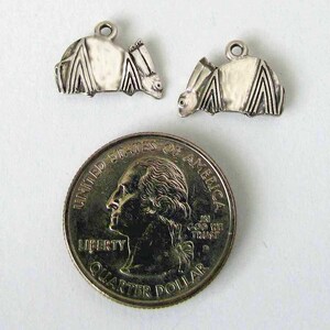 May include: Two silver bat charms with detailed wings and a textured surface. The charms are shown next to a US quarter for size reference.