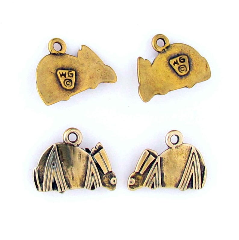 May include: Four gold-colored metal charms in the shape of a bat. Two of the charms have the letters "WG" and a circle design on the back.