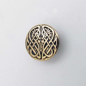 May include: A gold-toned metal button with a Celtic knot design. The knot is intricate and detailed, and the button has a smooth, polished finish.