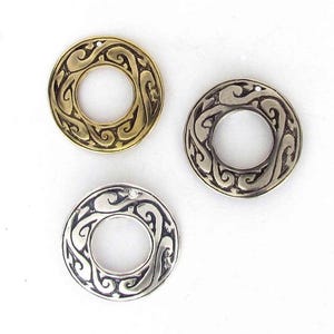 May include: Three metal rings with an intricate swirl design. The rings are in gold, silver, and antique silver.