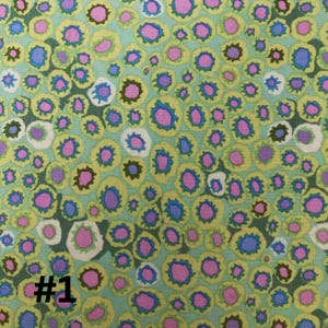 May include: A green fabric with a repeating pattern of pink, blue, and yellow circles. The circles have a white center and a dark green outline. The fabric has a #1 printed on the bottom left corner.