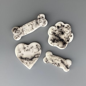 May include: Four ceramic tiles in the shape of a bone, paw print, and heart. The tiles are white with black swirling patterns.
