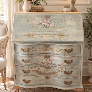 May include: A light blue painted secretary desk with a drop-down front and four drawers. The piece features gold-toned metal hardware, floral motifs, and French text including "LES ROSES DE SAADI" and "RAPPORTER DES ROSES" on the drawer fronts.